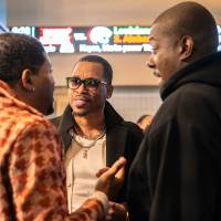 Group of three event attendees standing in circle together chatting